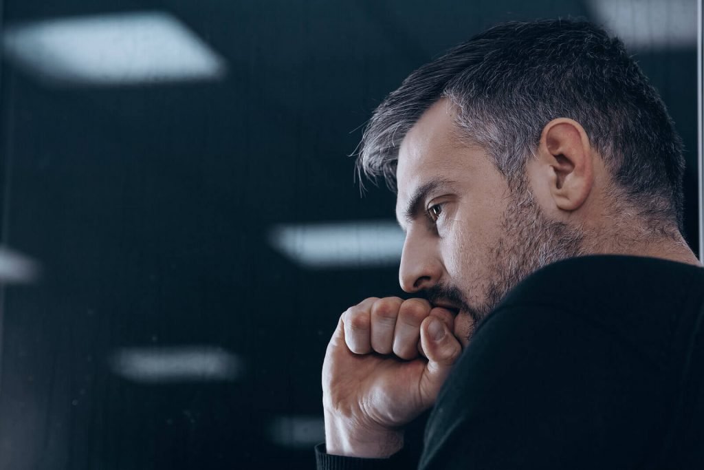 anxious man | neurofeedback therapy for anxiety in englewood, co | neurofeedback colorado | neurofeedback englewood | neurofeedback and anxiety | neurofeedback therapy | 80126 | 80129 | 80130 Image of an anxious man holding his fist to his mouth and wearing a black shirt. If you struggle with anxiety, learn how effective neurofeedback therapy for anxiety in Englewood, CO can help you cope.