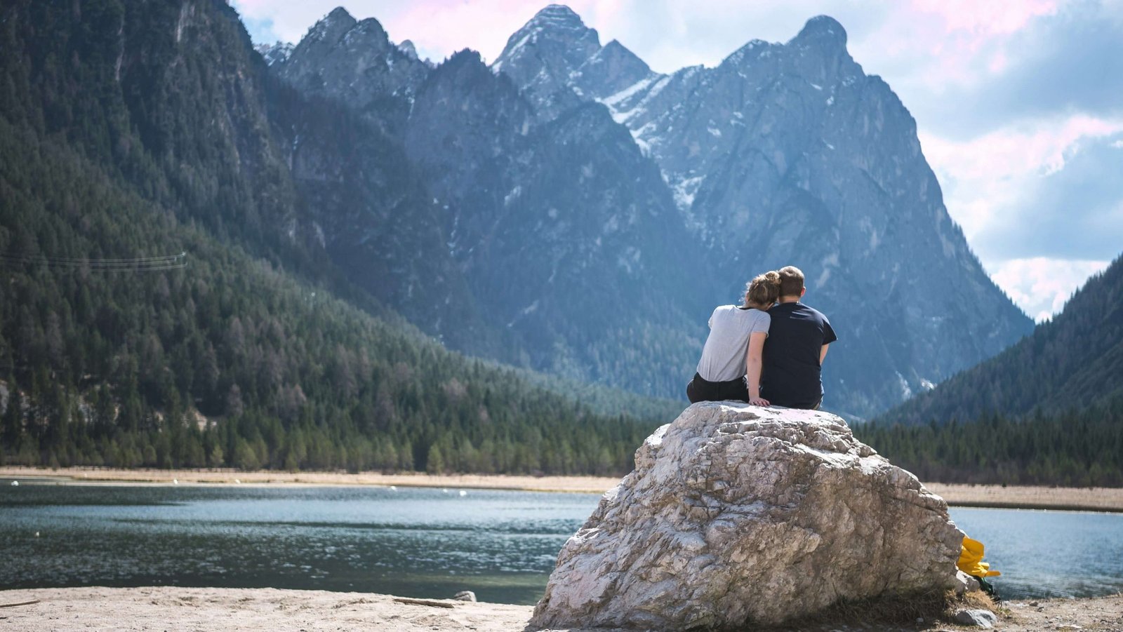 Image of a woman leaning her head on a man's shoulder while sitting on a rock looking at a lake and mountains. Discover how couples therapy in Greenwood Village, CO can help you and your partner rebuild your connection. Find support with the help of a couples therapist.