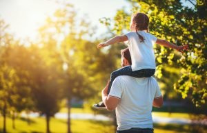 A child rides on the shoulders of their father as they walk through a sunny field. Learn more about how a family therapist in Englewood, CO can offer support with parenting styles. Search for family counseling in Englewood, CO for more parenting tips today. 