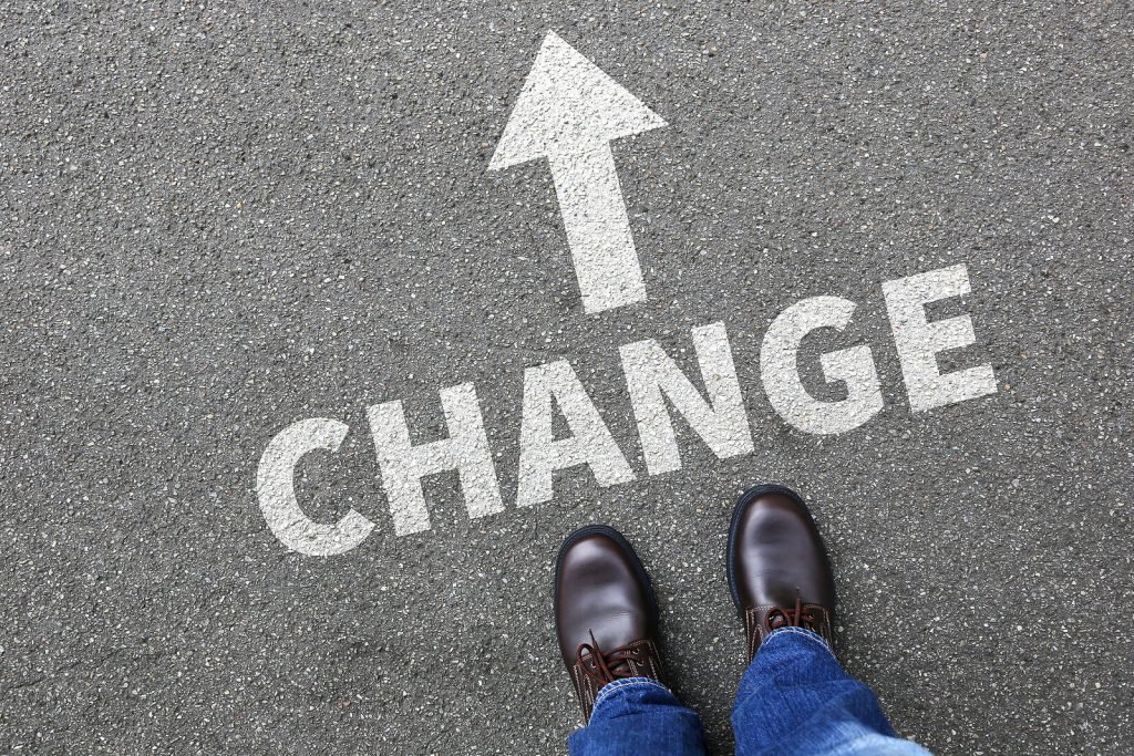 A close up of shoes standing in front of text on the ground and an arrow. The text reading "change" could represent the beginning of a transition in life that an anxiety therapist in Englewood, CO can help you navigate. Learn more about online therapy in Colorado and search for anxiety therapy in Englewood, CO or Littleton, CO.