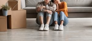 A couple sit on the ground next to one another against their couch with stressed expressions. The moving boxes to the left could symbolize the stress of a move that an anxiety therapist in Englewood, CO can help you cope with. Learn more about social anxiety treatment in Englewood, Co and how anxiety therapy in Greenwood Village, CO can help. 