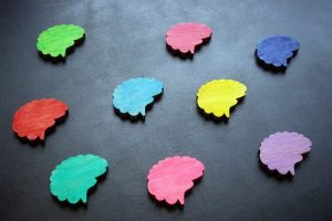 An image of multicolored wooden brains, representing the neurodiversity of ASD that an autism therapist in Greenwood Village, CO can help you address. Learn more about telehealth therapy in Englewood, CO and how autism testing for adults Colorado can help. 