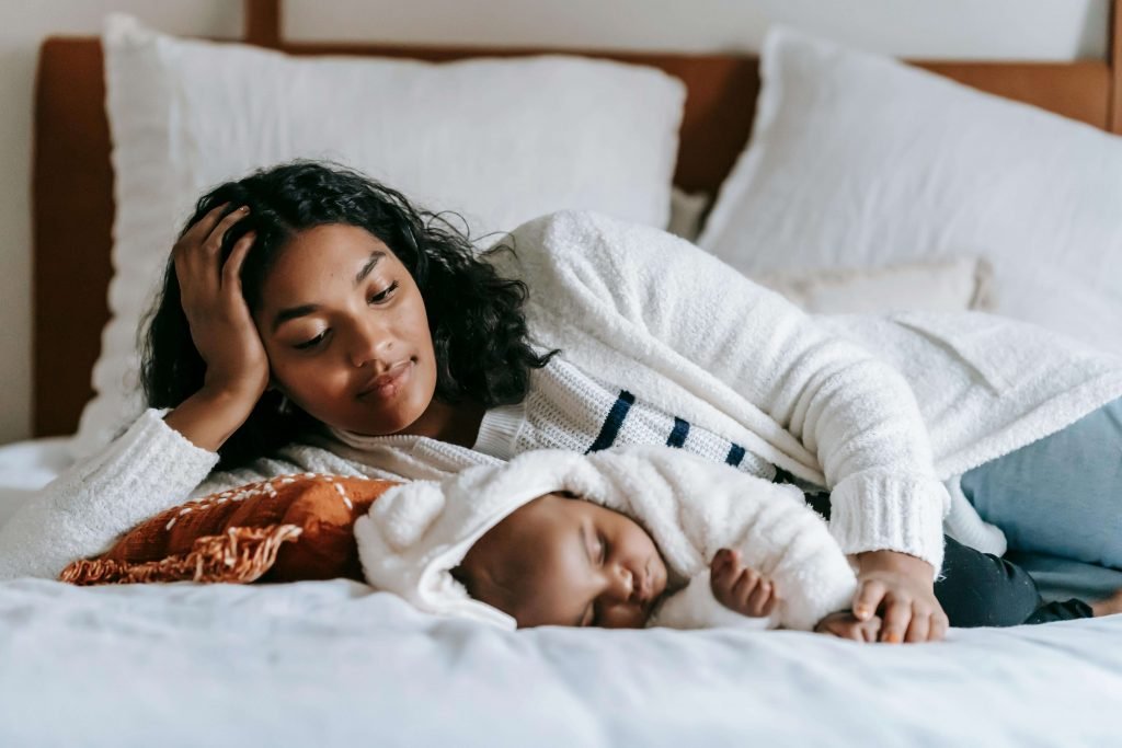 A woman is lying next to her baby in bed. While motherhood is a joyous period of life, it also comes with its challenges. Learn how postpartum depression counseling in Englewood, Colorado, can help you let go of burdens and doubts.