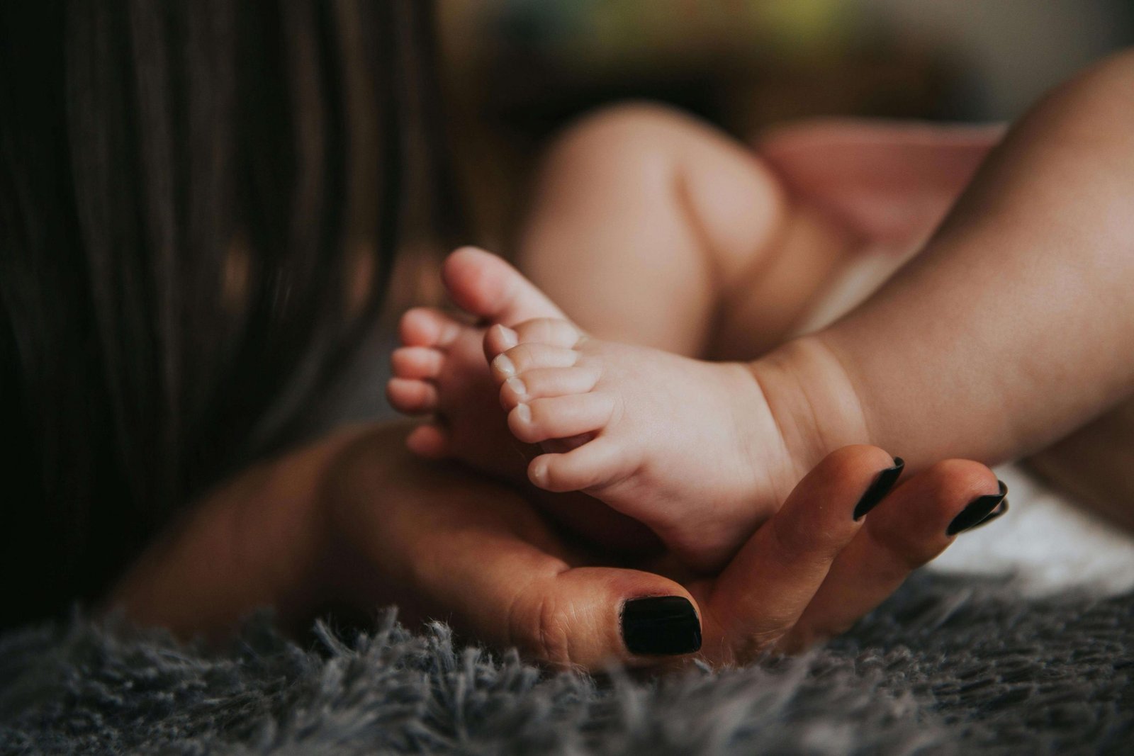A woman with painted nails lovingly holds her baby’s feet in her hands. Ensure your baby blues aren't actually postpartum depression with help from a maternal mental health therapist in Littleton, CO. Seek postnatal therapy today for guidance and peace of mind. 