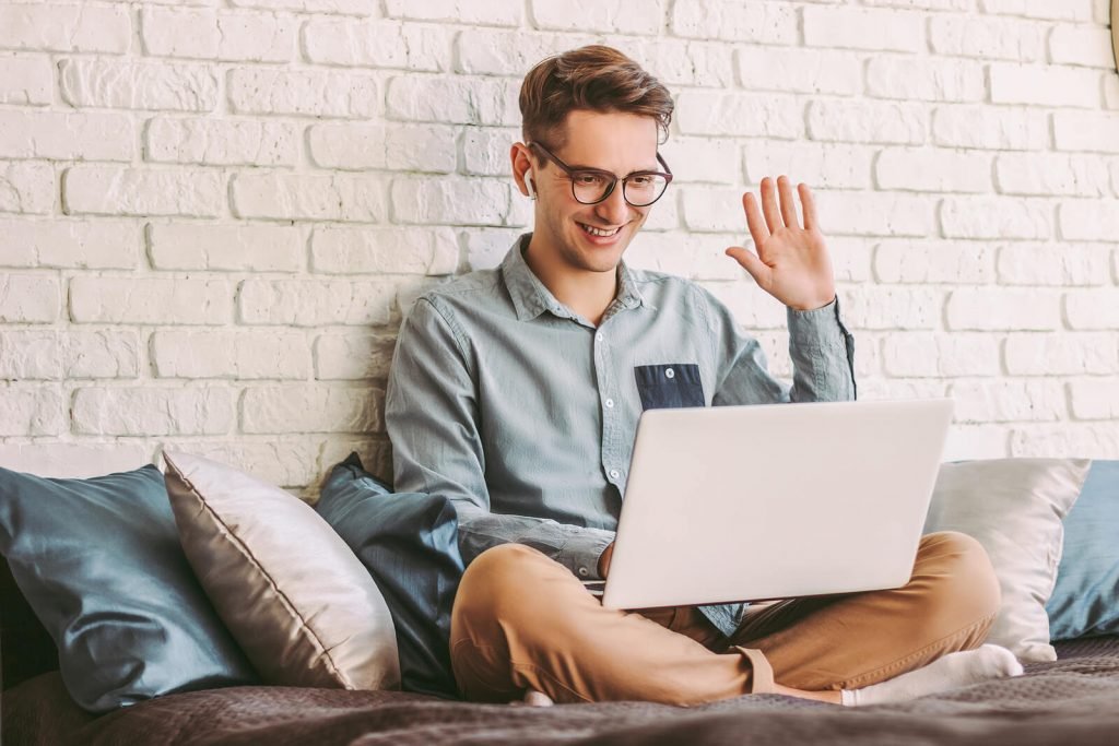 Image of a man waving at a laptop screen. Discover the benefits of online therapy in Colorado. Gain convenient access to couples counseling, treatment for depression and anxiety, and EMDR online in Denver, CO.
